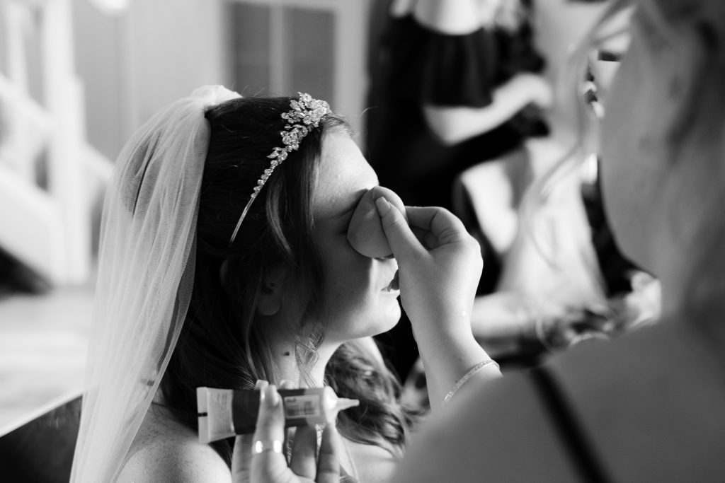 Bride getting her makeup done by her bridesmaid