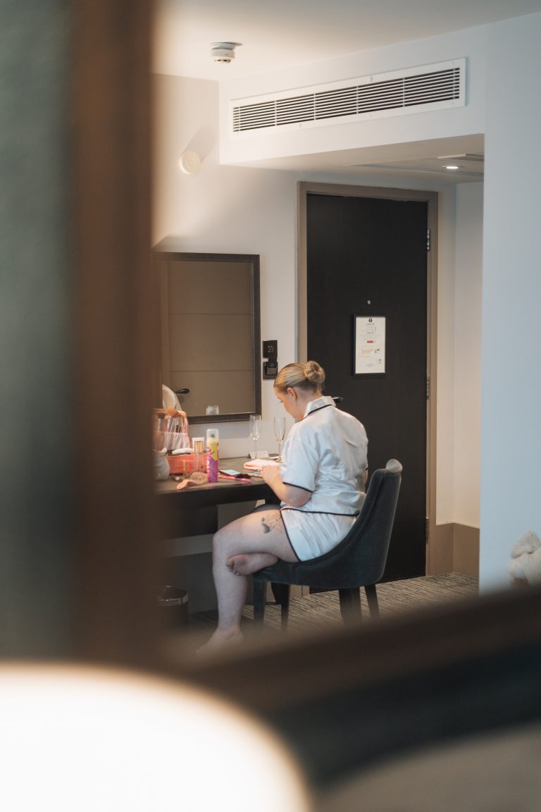 Looking into a window and seeing the bride getting ready at a table.