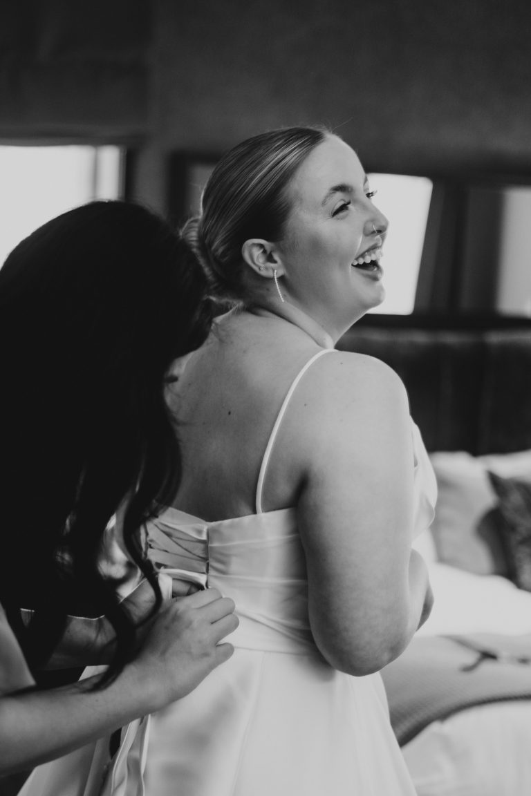 Bride laughing at something the bridesmaid said.