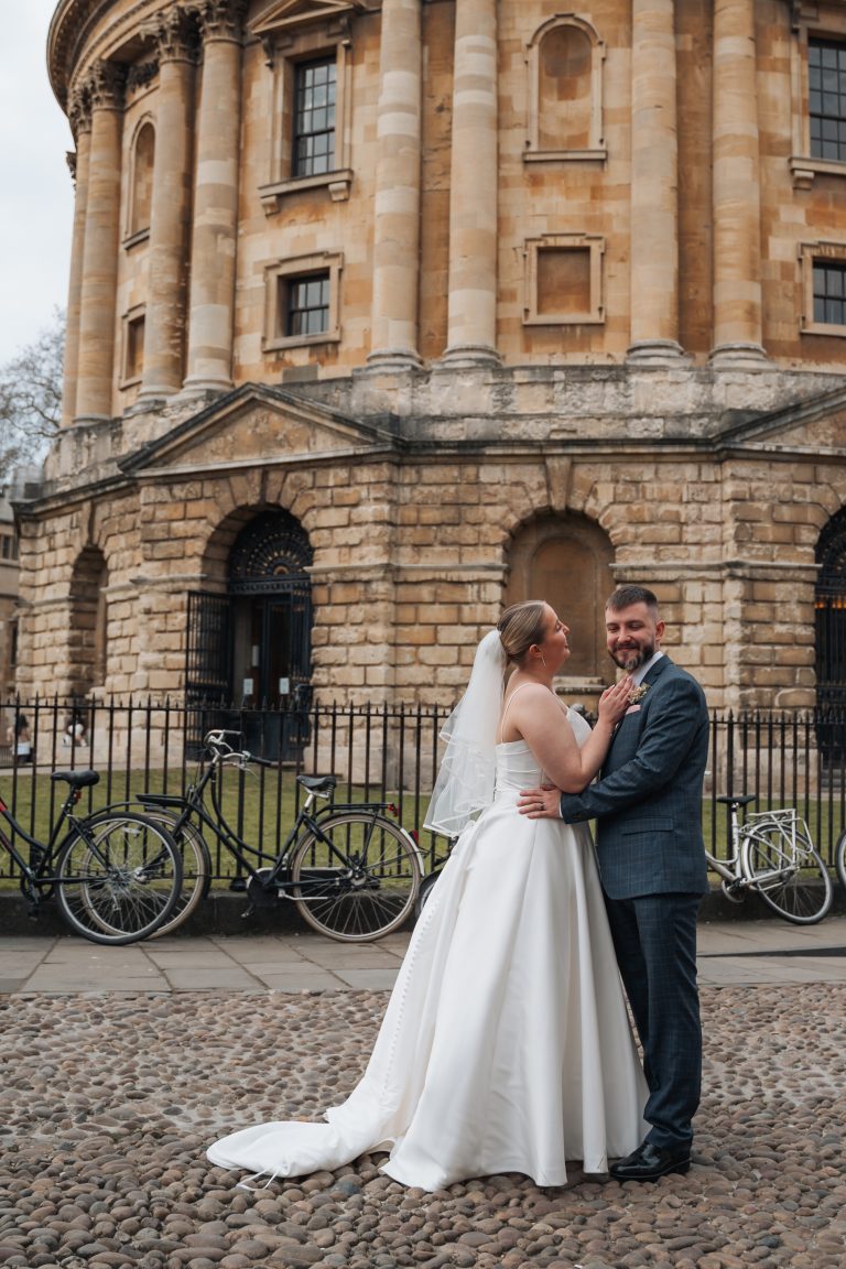 Bride sorting out the groom's outfit in front of the Radcliffe Camera in Oxford City centre.